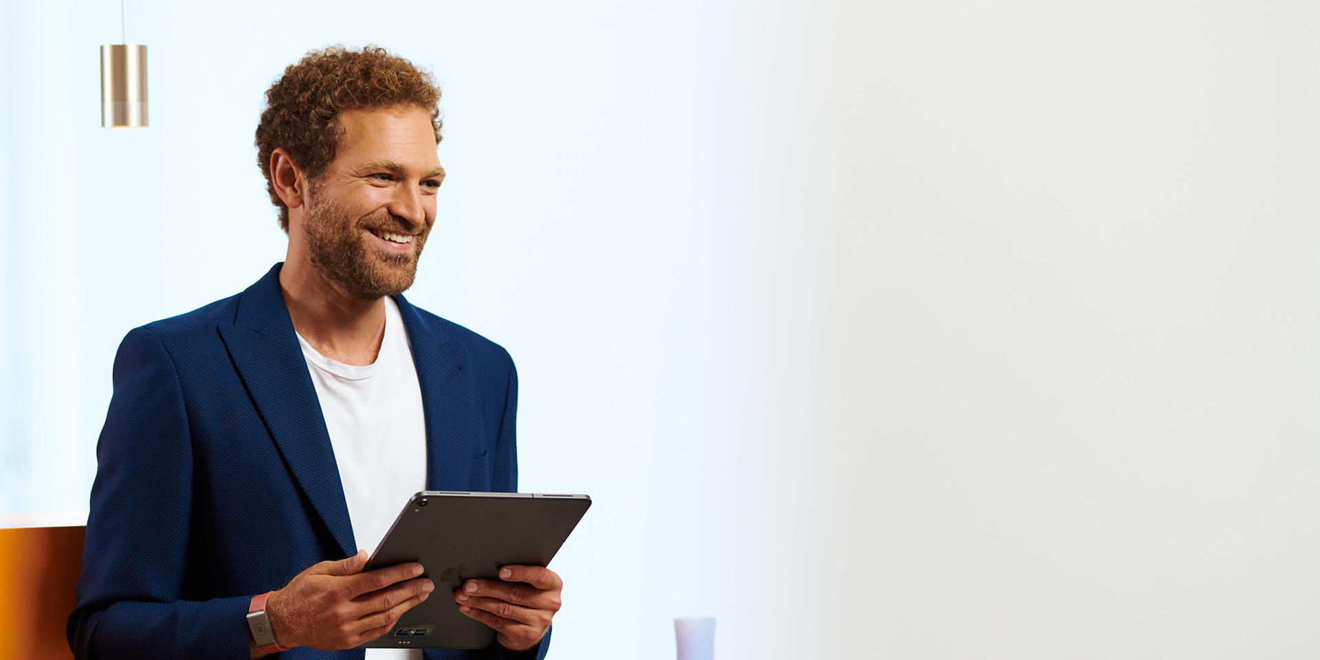 Happy man Man leans with his back against the counter and holds an iPad in his hand