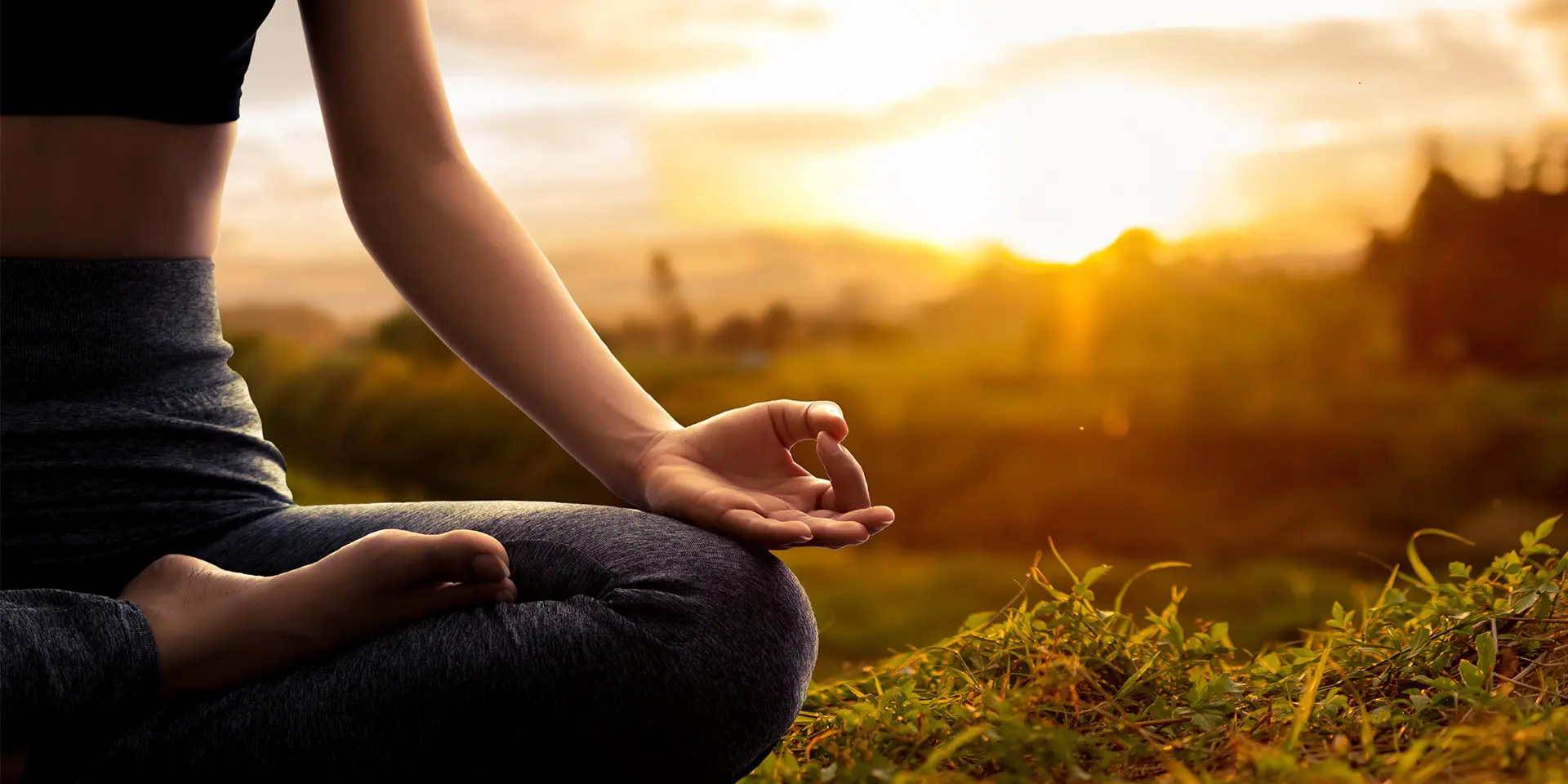 Frau sitzt in der Natur und macht Yoga 