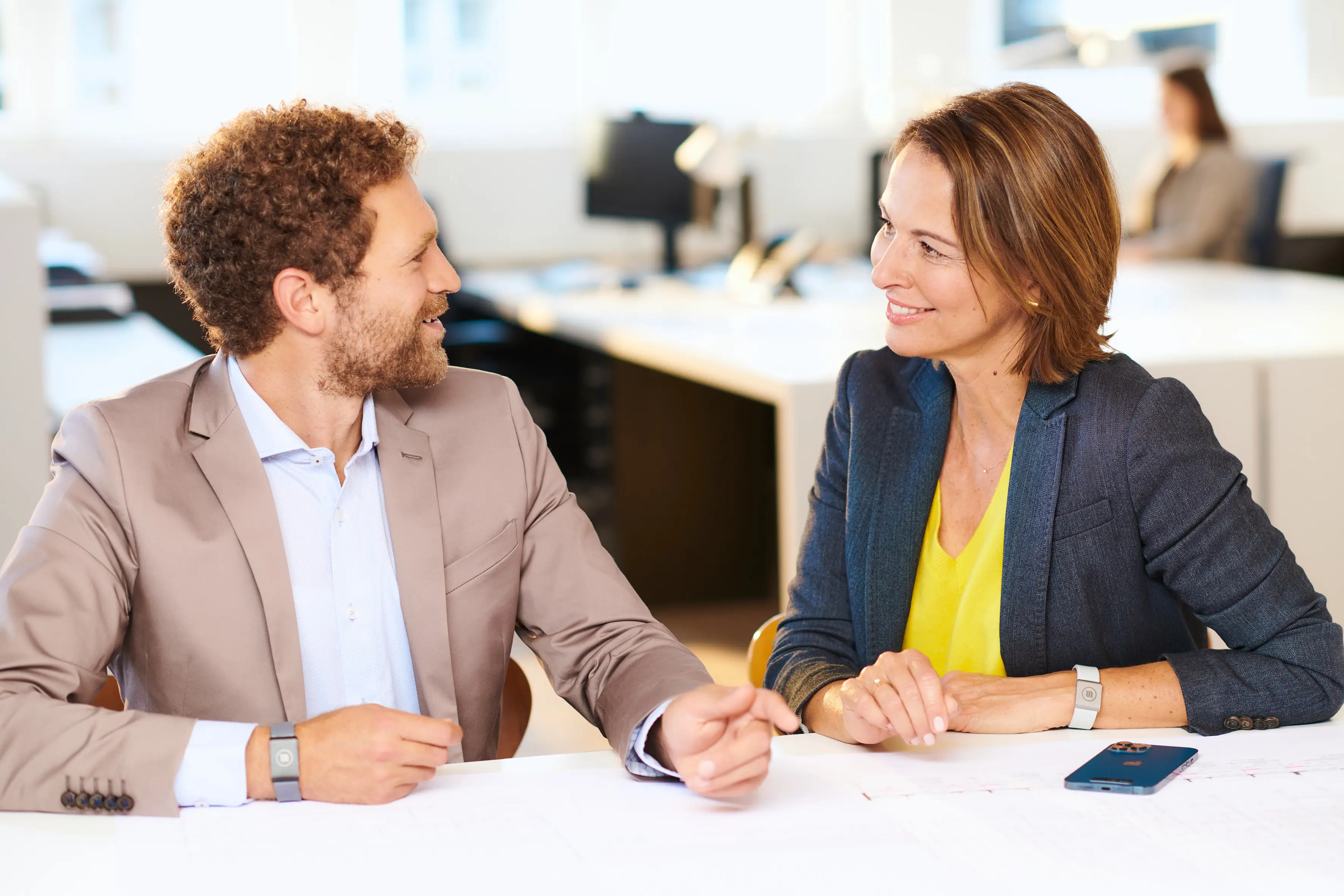 Employees sit around a table at a meeting and chat