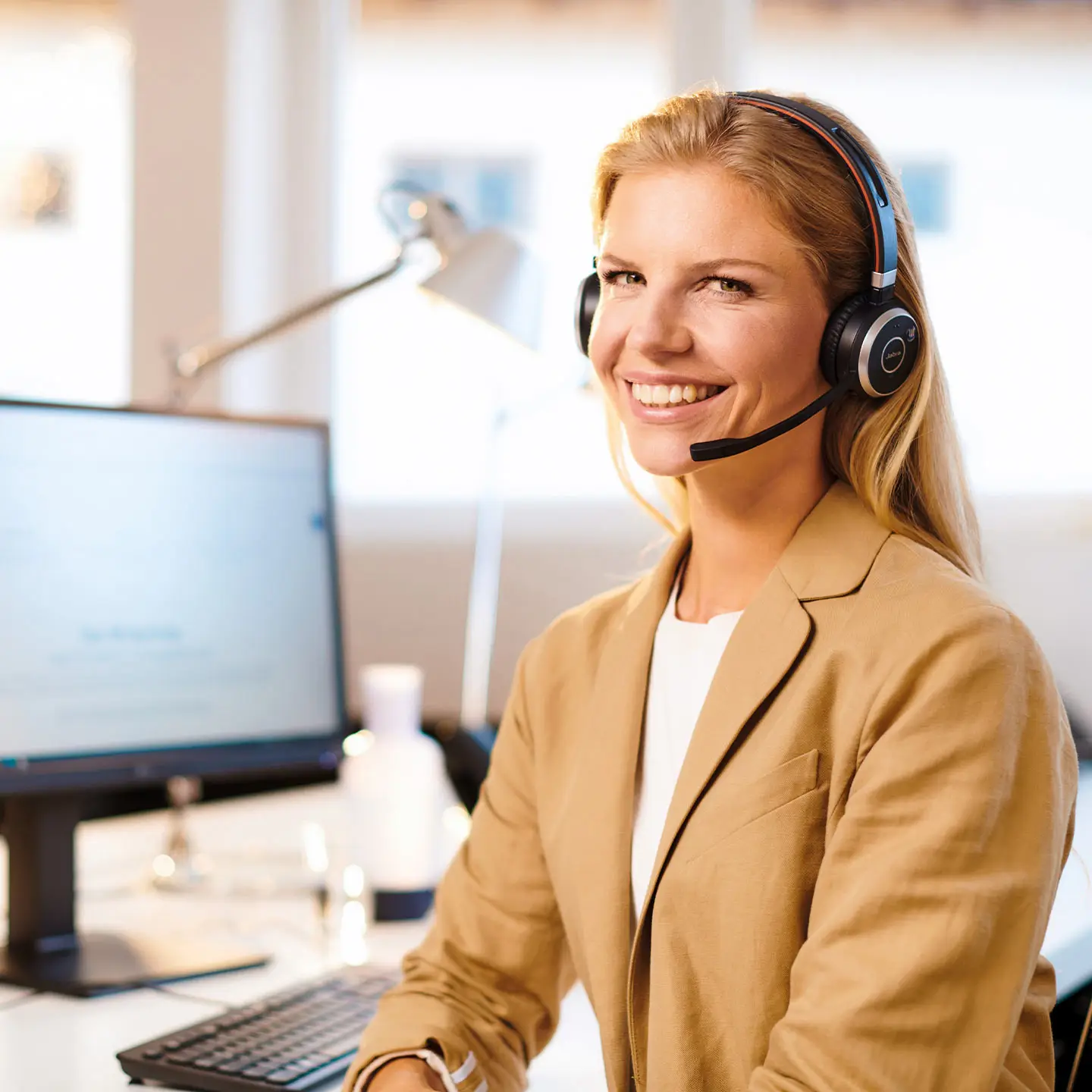 Frau am Schreibtisch mit Headset telefonierend