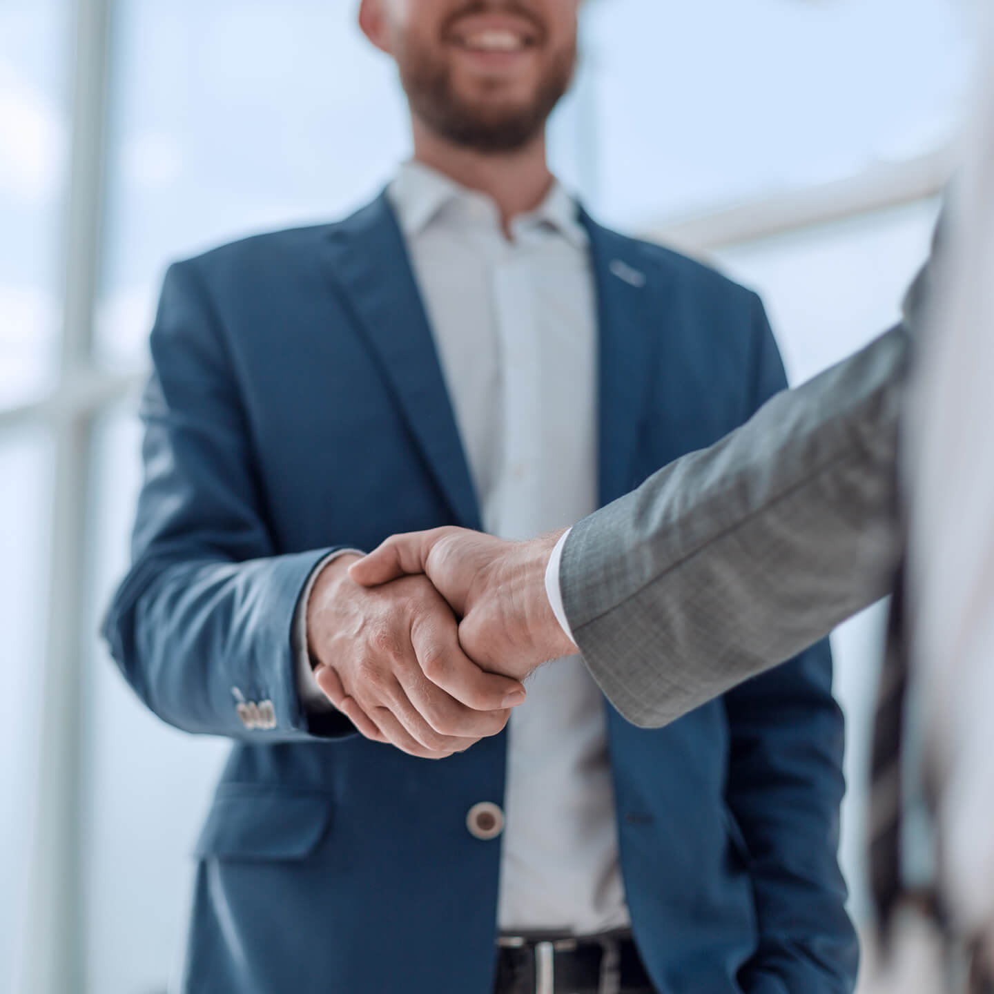 Man in blue suit shakes hands with business partner