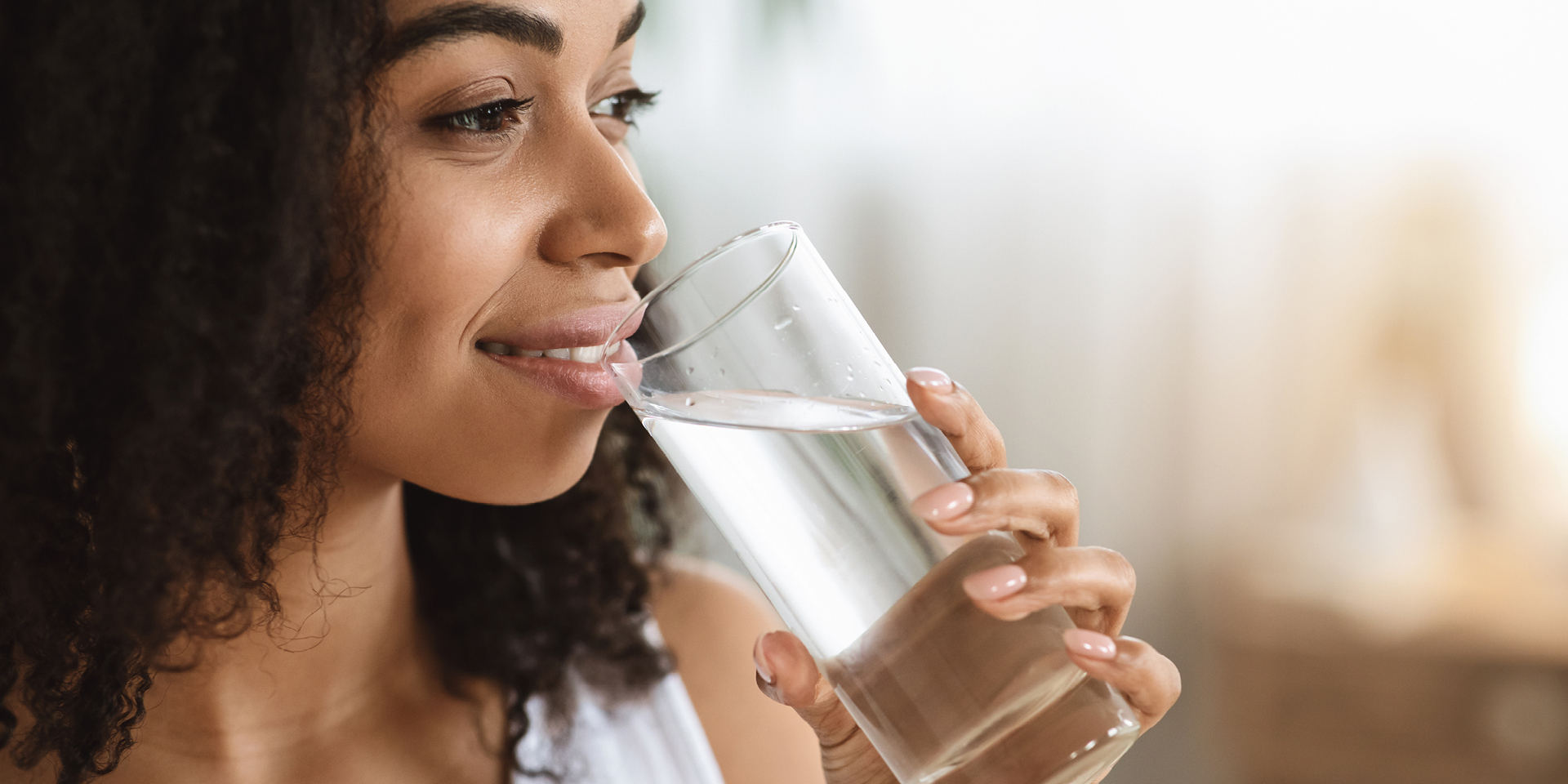 Welches Wasser ist das beste für uns? Frau trinkt ein Glas frisches Wasser