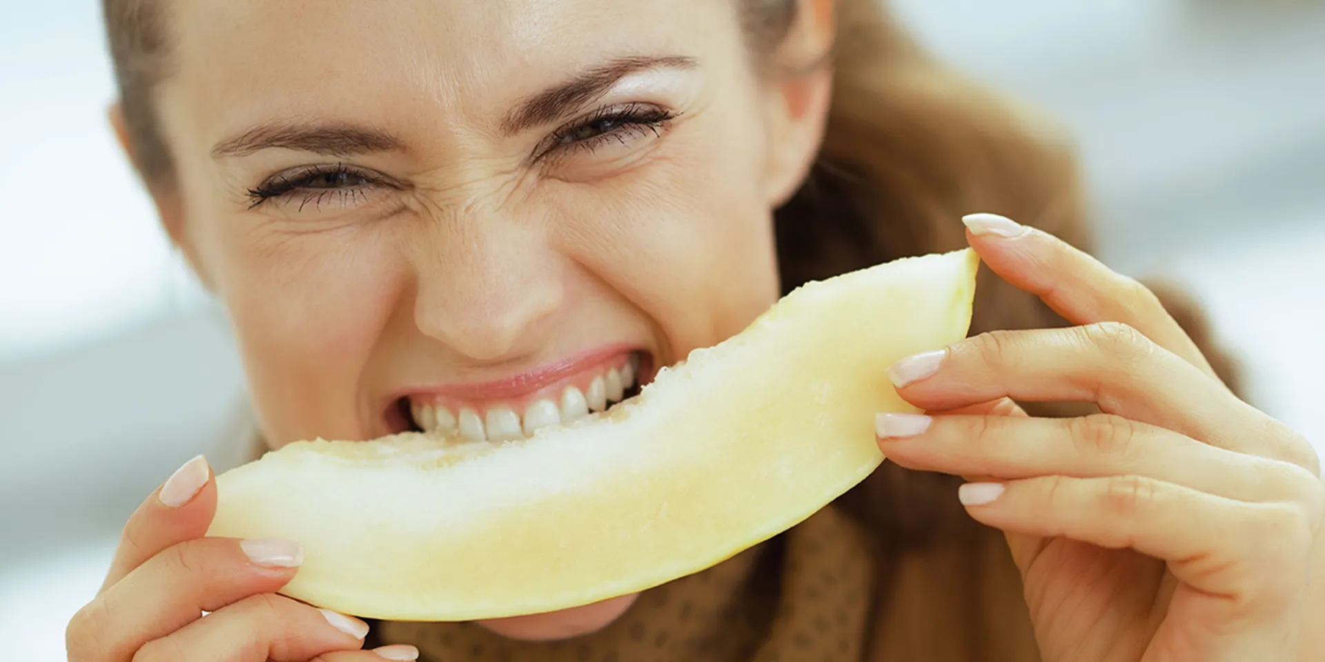 Frau beisst genussvoll in eine Melone