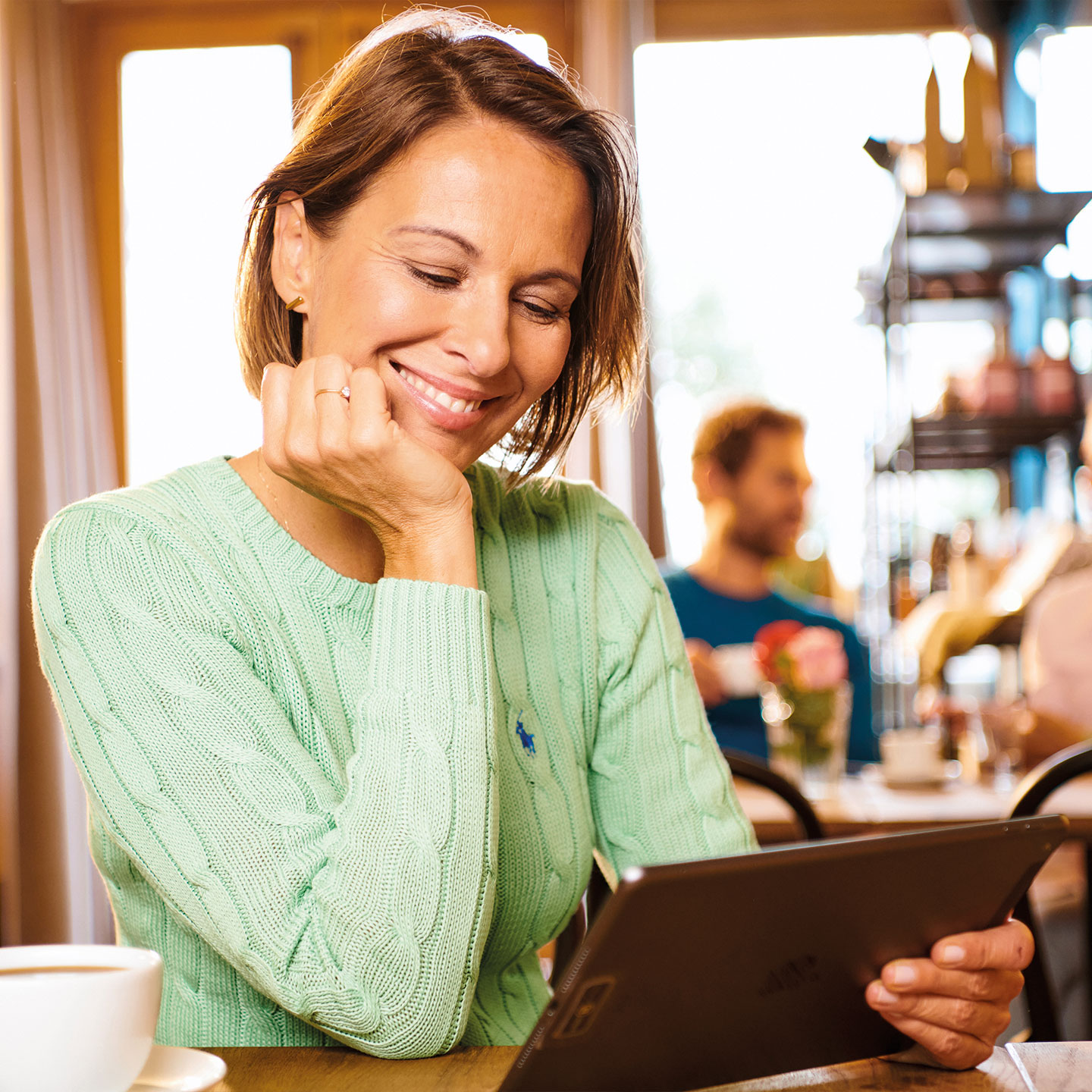 Eine Frau im Café sitzt an ihrem iPad
