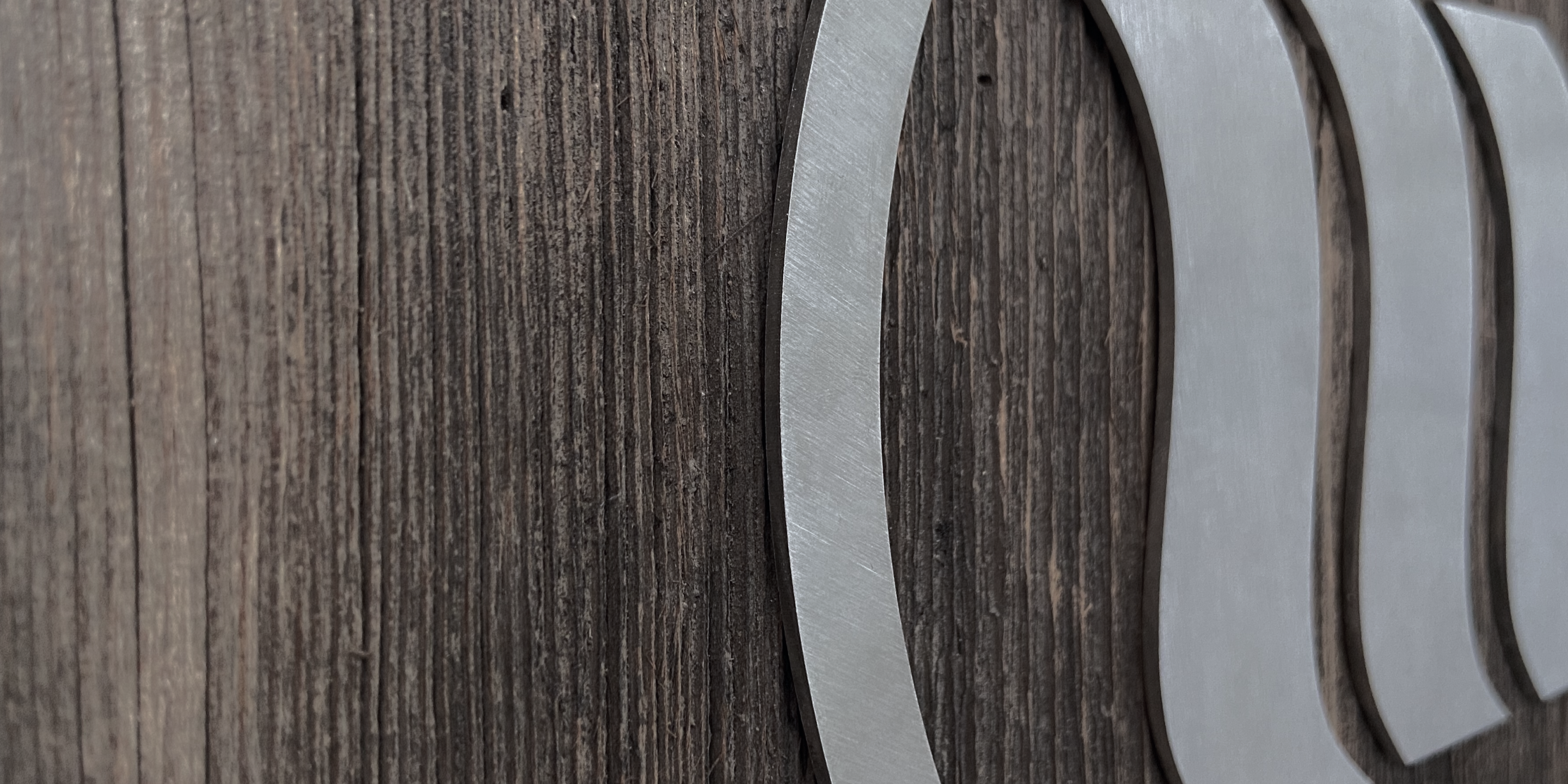 Un logo memon argenté en métal sur un fond brun en bois