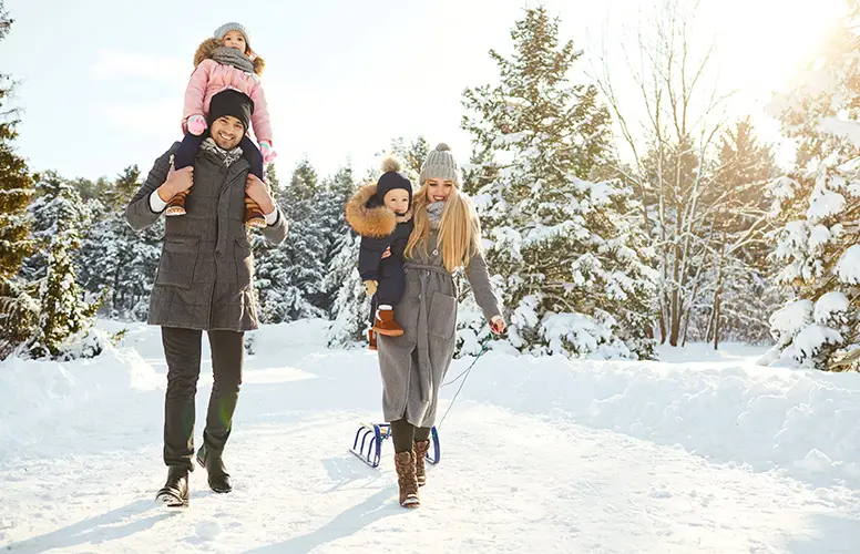 Familie beim Spaziergang im Schnee mit Kinder und Schlitten