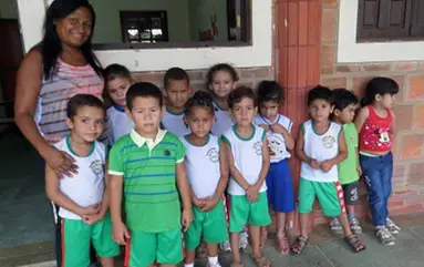 De pauvres petits Brésiliens avec une éducatrice devant une maison délabrée.