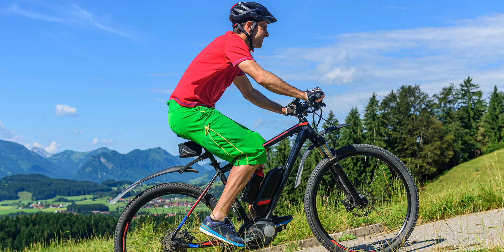 A sporty man rides an e-bike up a mountain