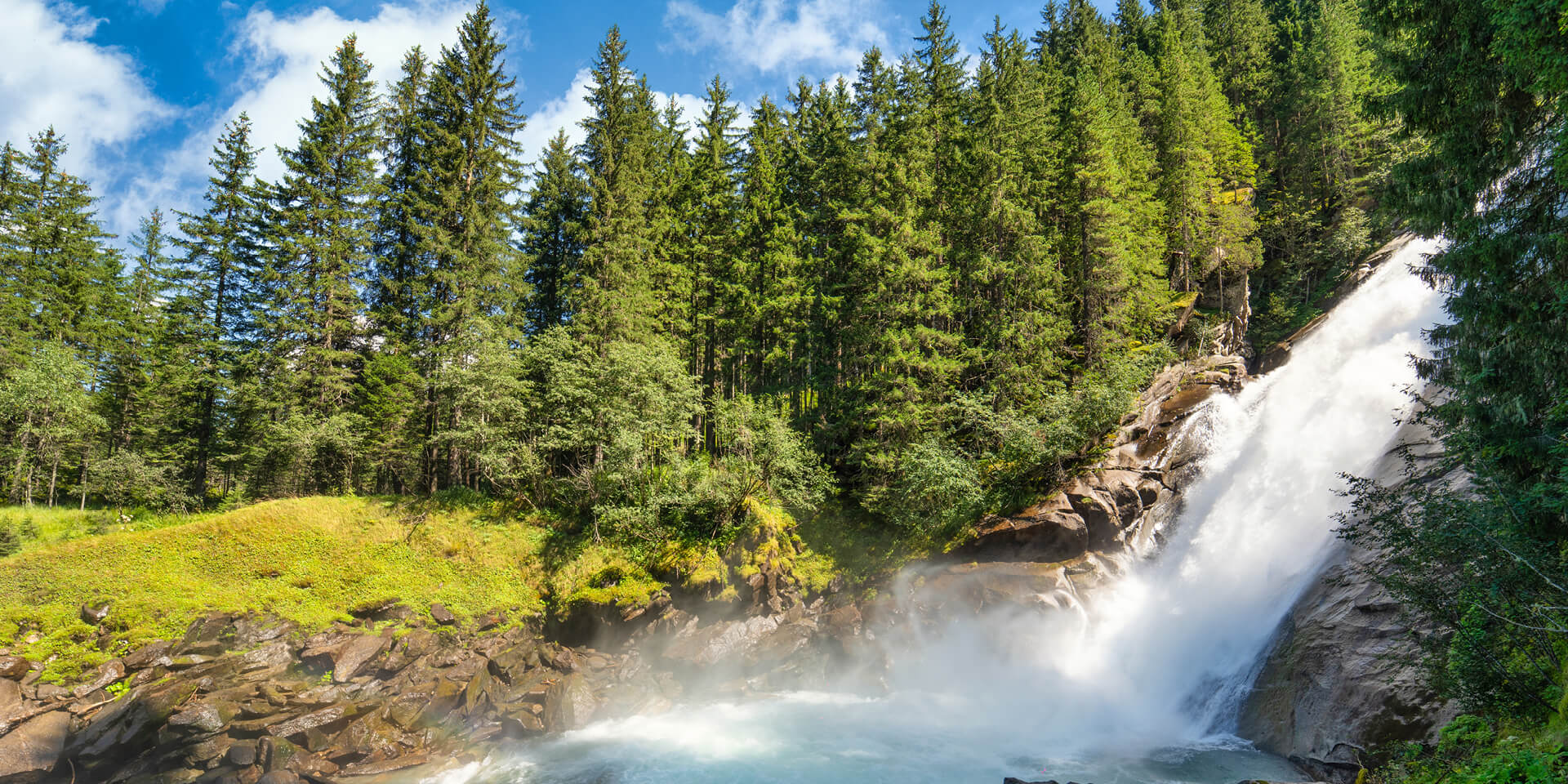 Natürlicher Wasserfall umringt von grünen Bäumen in der Natur