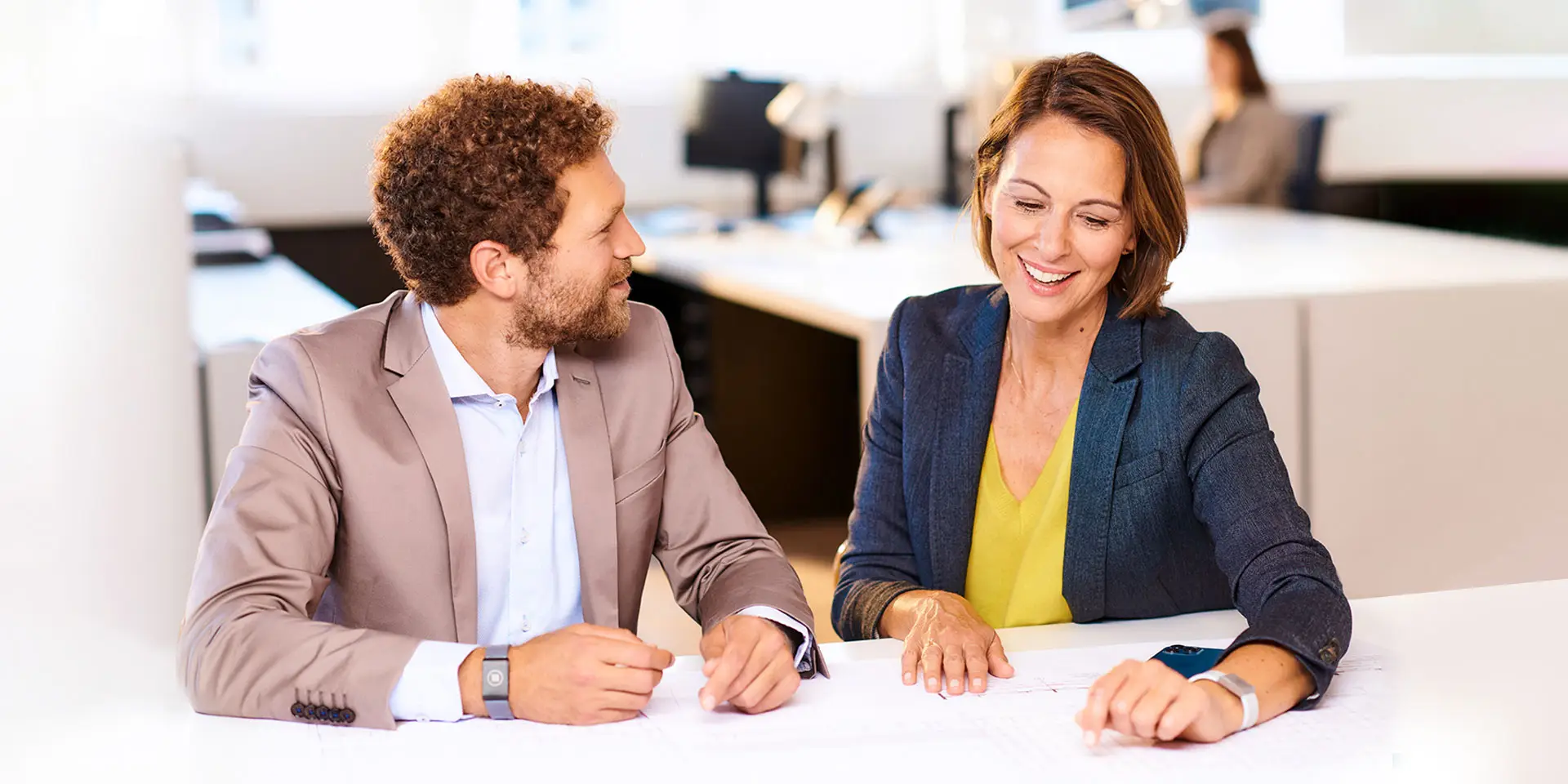 Employees sit around a table at a meeting and chat